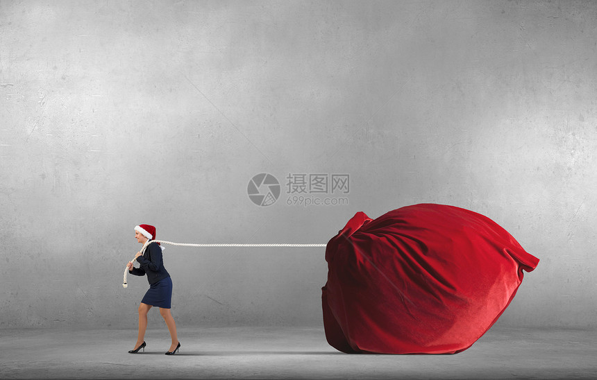 带着袋的诞老人戴诞帽的女人着巨大的红色礼物袋图片