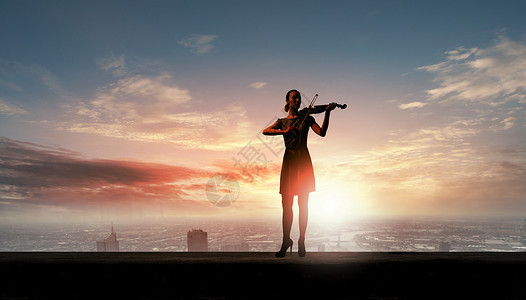 女小提琴手日出时拉小提琴的女人的剪影图片