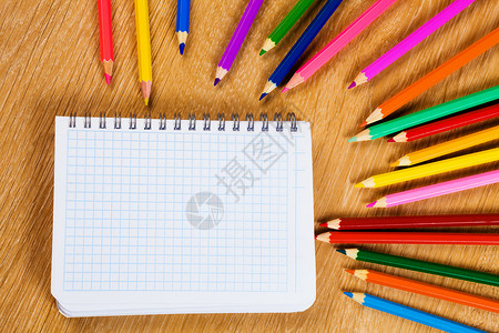 学校固定木制桌子上的彩色铅笔记事本背景图片