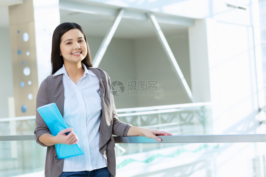 办公楼里魅力的女人轻的黑发女人现代璃内部与文件夹手图片