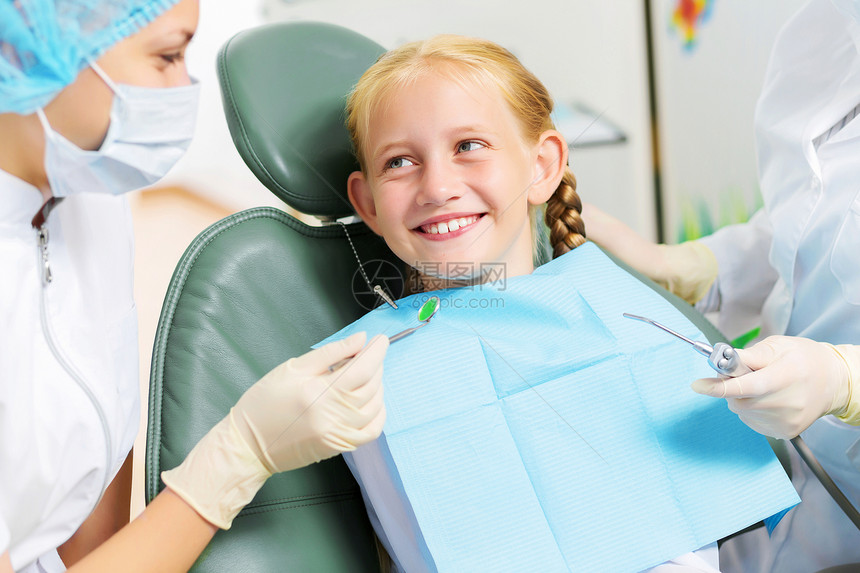 牙齿检查可爱的微笑女孩坐扶手椅上看牙医图片