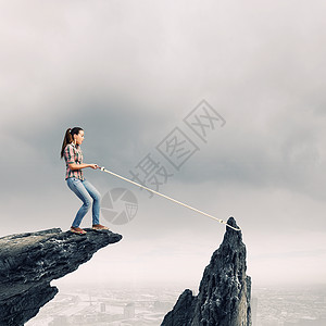 女人岩石上轻的女人穿着休闲的绳子抓石头图片