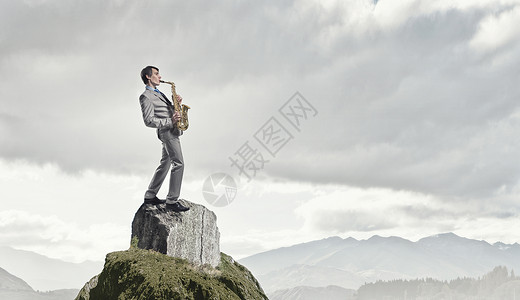 英俊的萨克斯演奏家岩石上演奏萨克斯管的轻人图片