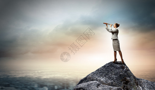 望远镜的商业女人女商人站岩石顶上用望远镜看的形象背景图片