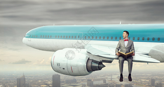 飞行飞机的机翼上轻的商人坐飞机上看书背景