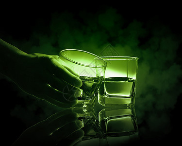 两杯绿色的苦艾酒手着两杯绿色的苦艾酒中的杯图片