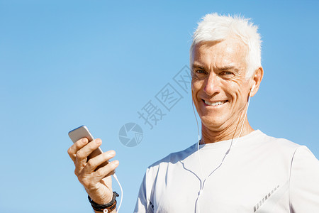 男跑步者,他的移动智能手机站户外轻的男跑步者,他的移动智能手机站户外图片