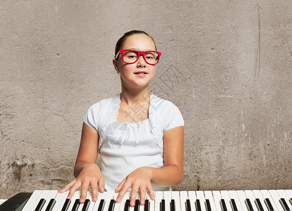 学钢琴的女孩戴着滑稽眼镜弹钢琴的漂亮女孩背景图片