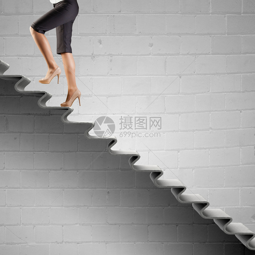 上职业阶梯轻的女商人走楼梯上,代表着成功的图片