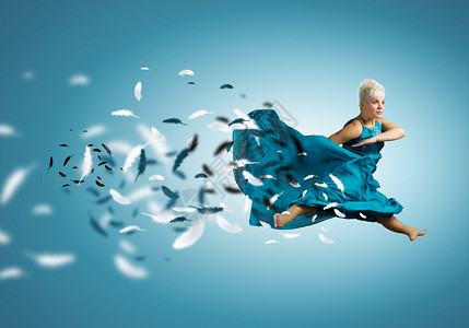 跳跃的女人轻迷人的女人穿着蓝色连衣裙跳得很高图片