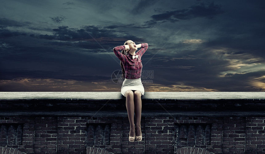 轻的女人坐屋顶上,用手捂住耳朵图片