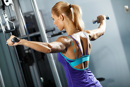 肩部锻炼健身女孩健身房锻炼哑铃的形象图片