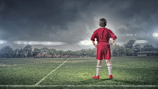 足球场上的小男孩足球场上穿红色制服的男孩的后视镜图片