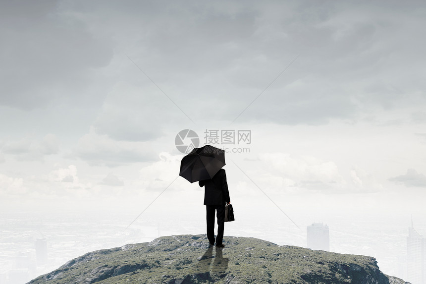 带雨伞的商人站山顶上的商人带着雨伞手提箱的背景图片