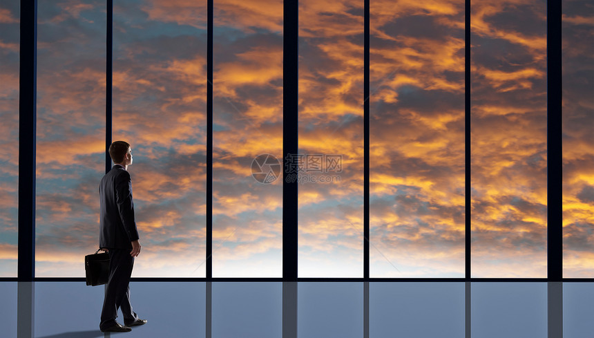 下个成功的日子商人办公室窗户上看日出的背景图片