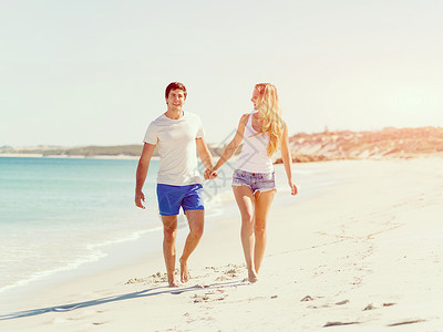 浪漫的轻夫妇海滩上浪漫的轻夫妇海滩上沿着海岸散步高清图片