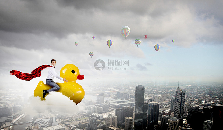 商人表现得像个孩子轻快乐的商人骑着黄色橡胶鸭图片