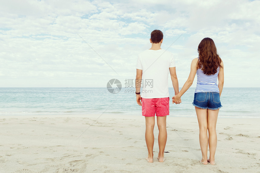 浪漫的轻夫妇站海滩上浪漫的轻夫妇站海滩上看着大海图片