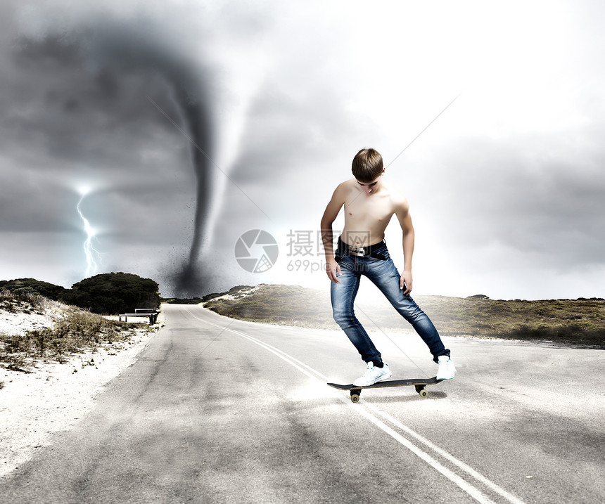 滑板上的青少溜冰者穿着牛仔裤路上,背景龙卷风图片
