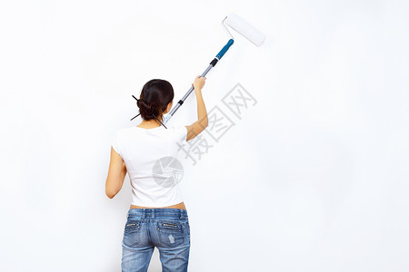 轻的女人用油漆刷翻新白色墙壁图片