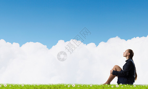 她处于困境孤立之中无聊的轻女商人独自坐绿色的草地上图片