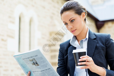 商业女人户外微笑的肖像轻商业女户外阅读报纸的肖像图片