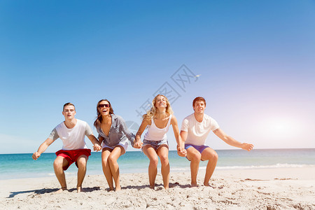 海滩上轻人的陪伴轻朋友海滩上玩跳跃的乐趣图片
