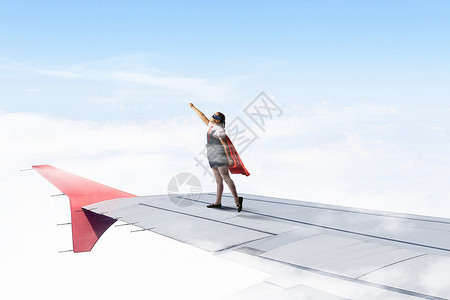 小超级英雄强大的超级英雄女孩站飞行飞机的机翼上图片