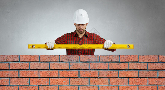 水平的建筑工人砖工用水平检查新红砖墙室外图片