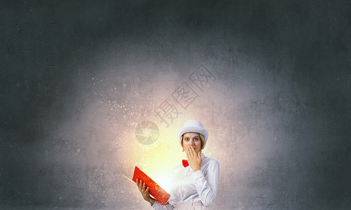 炸毁你想象力的书轻的女人戴着白色的帽子,手里着打开的红皮书图片