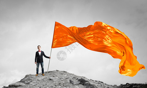 橙色挥舞的人学生家伙穿着休闲,手里着旗子图片