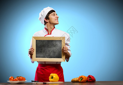 轻的厨师英俊的厨师着空白的粉笔板文字的位置图片