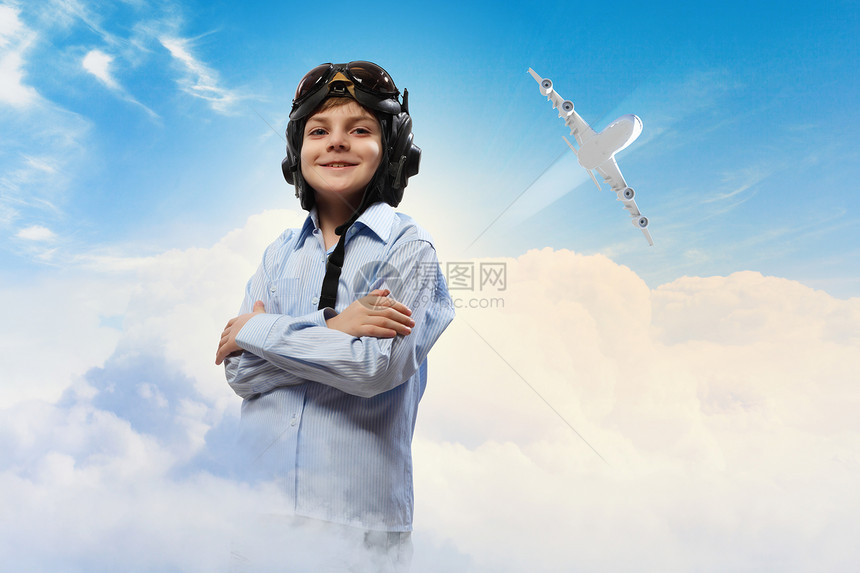 戴着飞行员帽子的小男孩飞行员头盔中小男孩的形象,背景为飞行飞机图片