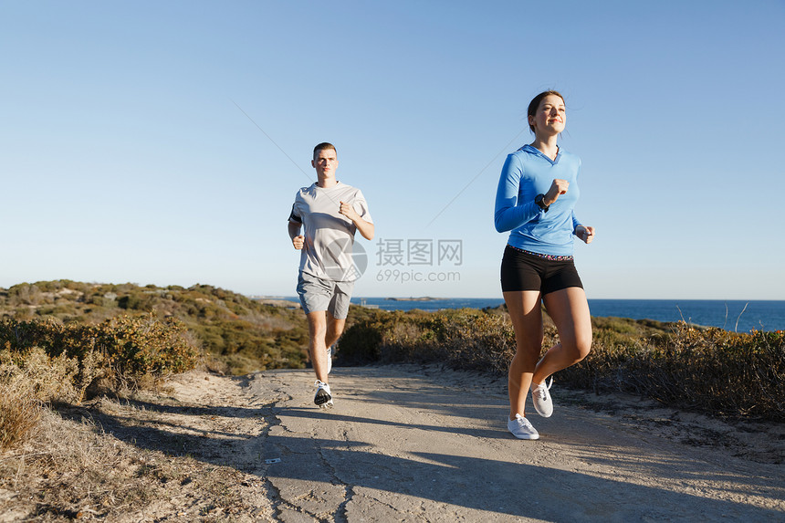 运动跑步者海滩上慢跑,她的搭档锻炼适合女健身模式慢跑沿海洋与她的伴侣图片