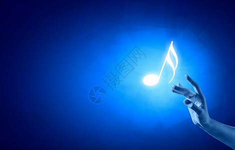音乐音符特写人手触摸蓝色背景上的音乐符号图片