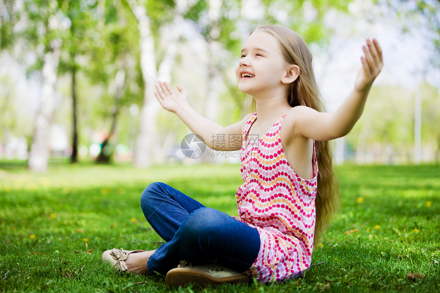 公园里的小女孩公园里坐草地上的小可爱女孩的形象图片