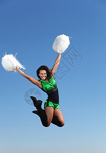 白色背景的轻女舞者穿着绿色服装的轻拉拉队长跳蓝天上图片