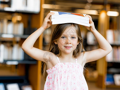 小女孩图书馆头上戴着本书读书可能很趣图片