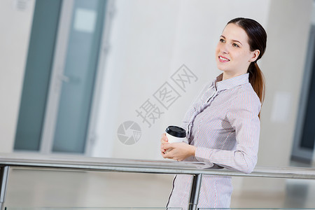 咖啡休息时间随意的白种女人站阳台上,手里着咖啡图片