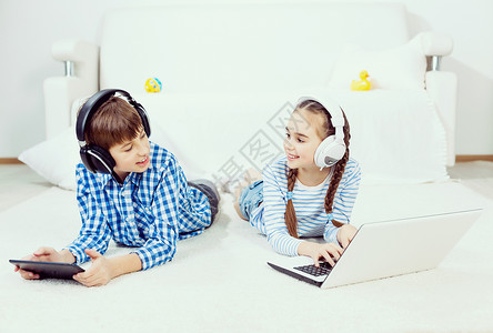 可爱的孩子用设备男孩女孩躺地板上用平板电脑笔记本电脑图片