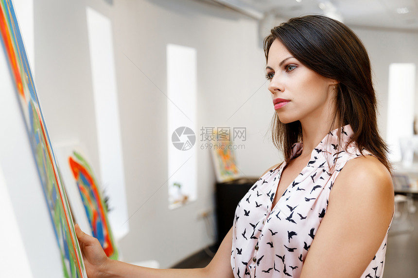 轻的白种人女人站画前的美术馆里轻的白种人女人站个艺术画廊前,画展示白色的墙上图片