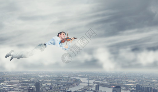商务休息轻的商人天空中飞翔,拉小提琴图片