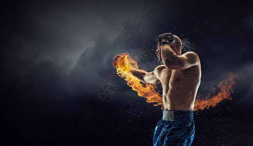 火焰拳箱式战斗机户外训练黑暗背景下的强壮拳击手展示了力量耐力背景