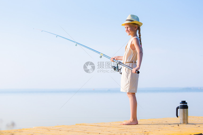 穿着连衣裙戴着钓鱼竿的帽子的女孩穿着连衣裙帽子的女孩带着钓鱼竿码头钓鱼图片