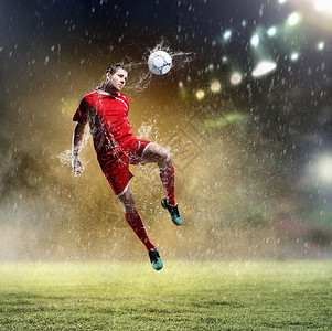 雨中足球足球运动员击球足球运动员穿着红色衬衫雨中体育场击球背景