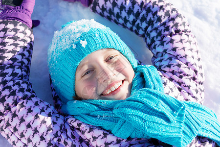 快乐的孩子躺冬天公园的雪地上图片