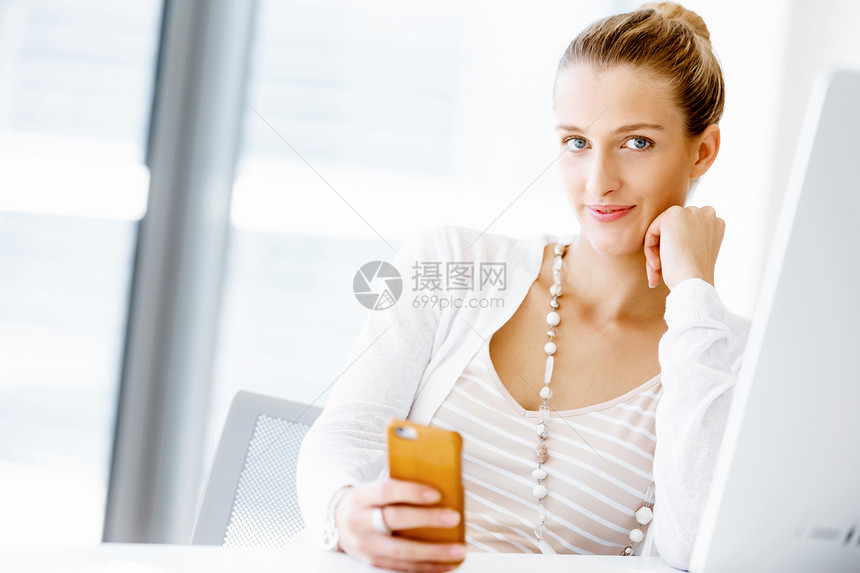 女商人坐办公室的桌子玩着手机图片