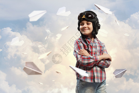 戴着飞行员帽子的小男孩飞行员头盔里的小男孩的形象,背景纸飞机图片