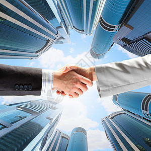 销售联盟素材商务握手近距离的手与摩天大楼的形象设计图片