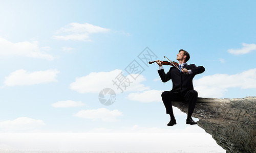 才华的人要站顶端商人坐岩石边缘拉小提琴背景图片